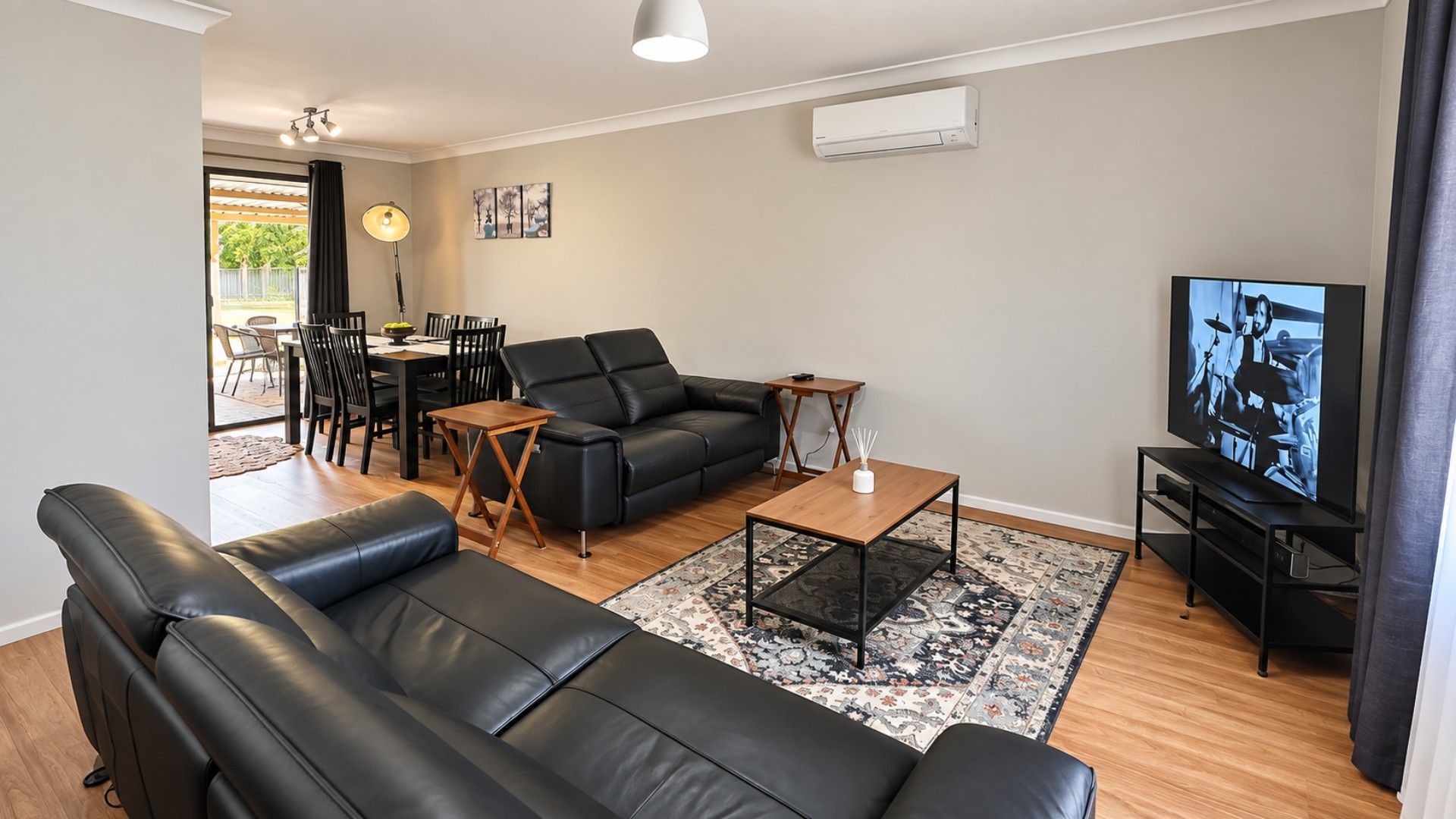 A modern living room with a black leather sofa, a wooden coffee table, and a television.