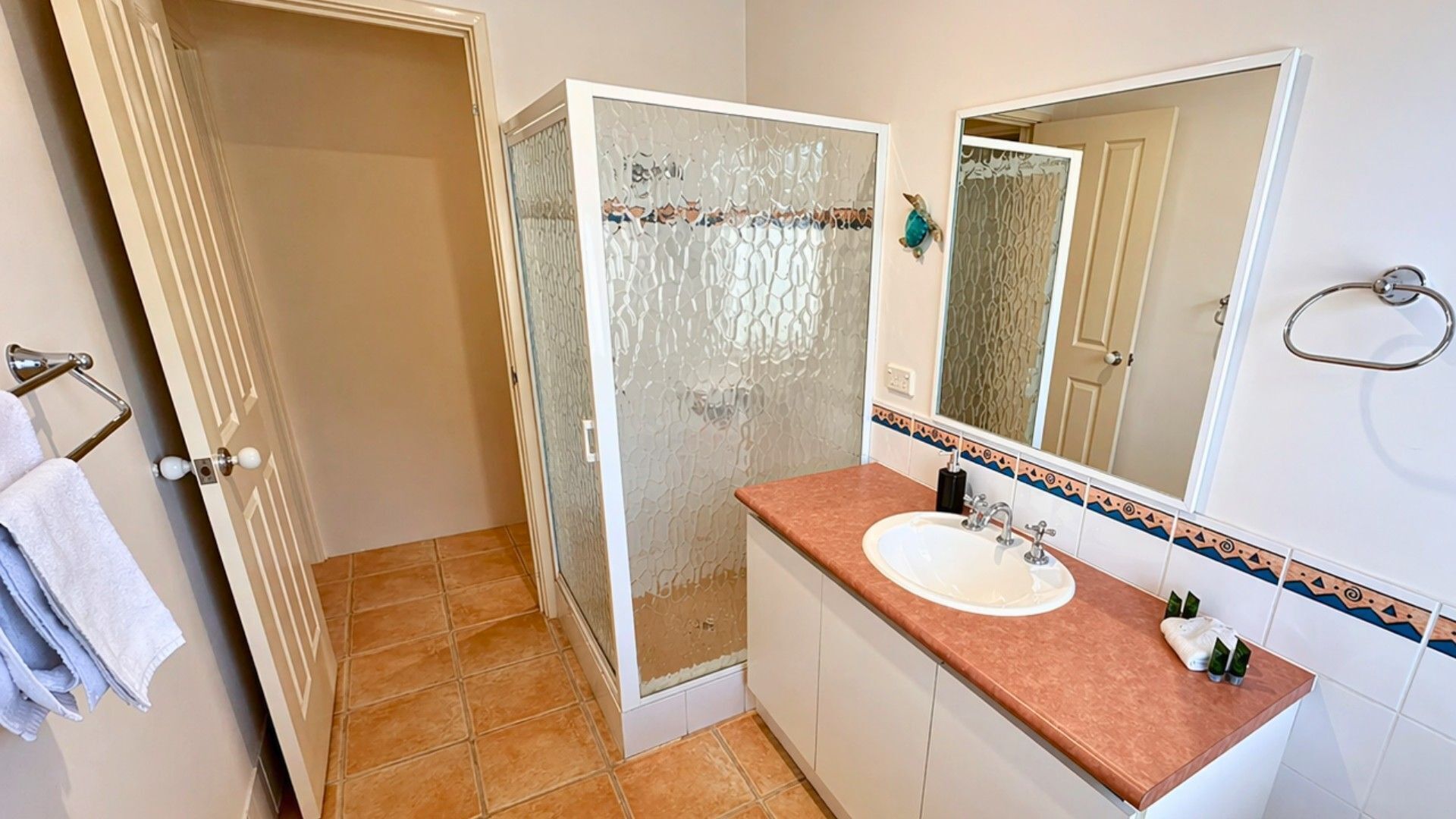 Un baño con ducha, lavamanos y espejo.