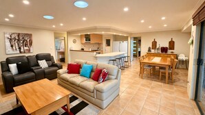 A living room with a sofa, a coffee table, and a dining area with a table and chairs. - Anne's Retreat - Busselton (West Busselton)