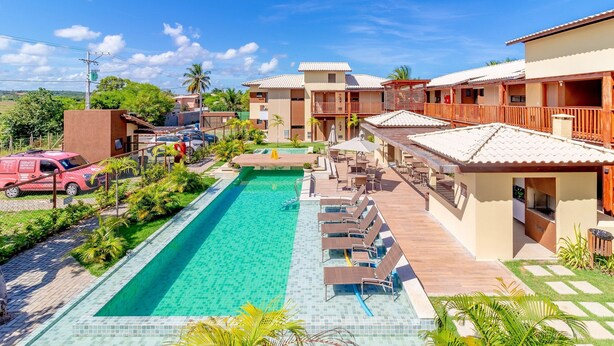 A resort with a swimming pool, lounge chairs, and a view of the surrounding landscape. - IT81 Great 3/4 Apartment (1 Suite) - Itacimirim (Camaçari)
