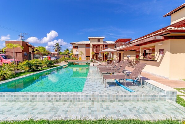 Relax by the pool surrounded by lush greenery and lounge chairs.