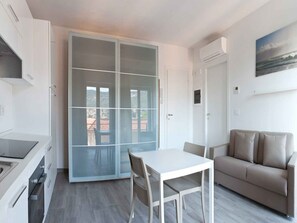 A modern living room with a white table, beige sofa, and a sliding glass door leading to a balcony.