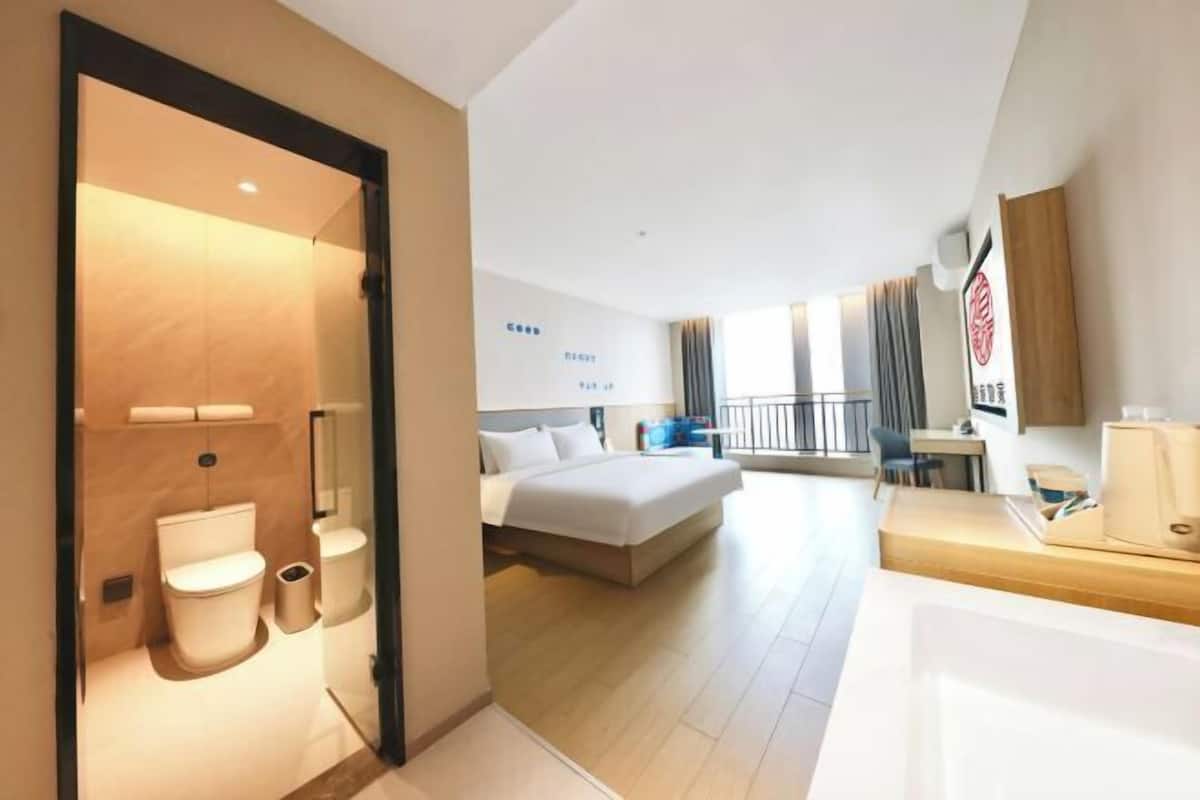 Une chambre d’hôtel comprenant un lit, une table de chevet et une salle de bain avec des toilettes et un lavabo.
