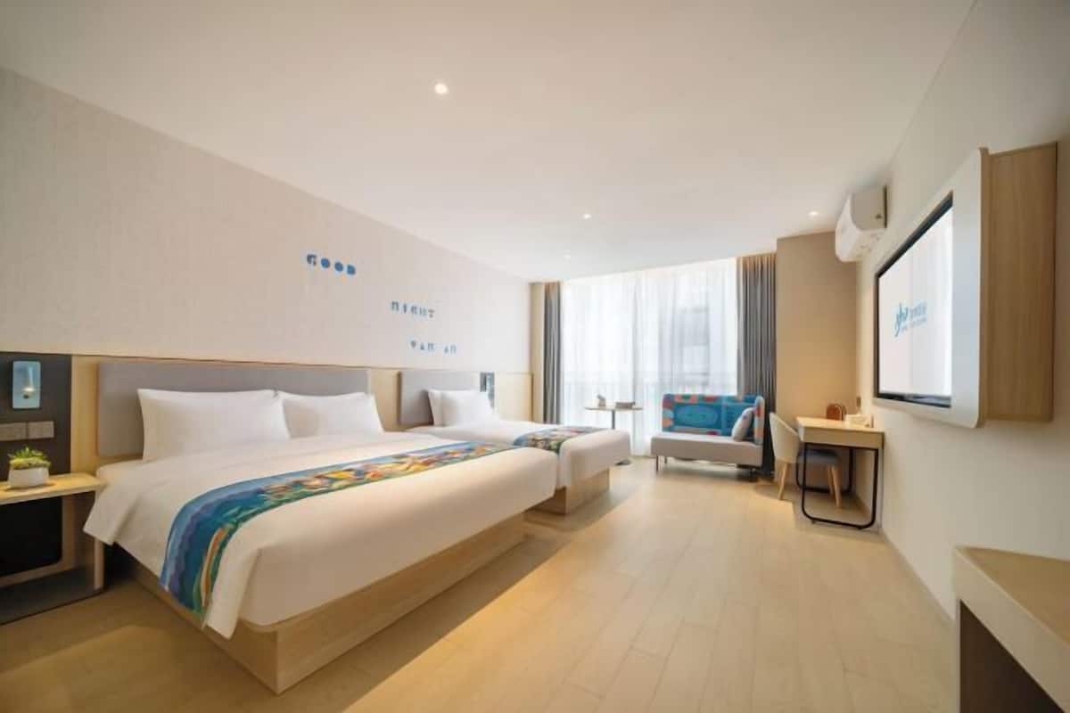 Une chambre d’hôtel avec un grand lit, un bureau, une chaise et un téléviseur.