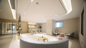 A modern interior with a central seating area, a kitchen in the background, and a large window on the right. - Homeinn · neo (Meishandong Railway Station Sansu Temple) (Meishan)