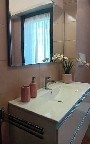 Une salle de bain moderne avec un grand miroir, un lavabo double et une plante en pot.