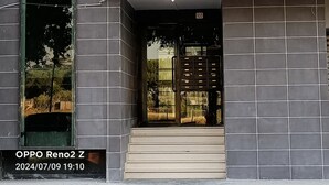 Ein modernes Gebäude mit dunkler Fliesenfassade, einem sichtbaren Fenster und einem kleinen Balkon.