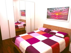 Une chambre à coucher avec un lit, une tête de lit en bois, un miroir et un tableau accroché au mur.