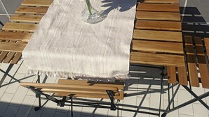 Ein Holztisch mit einer gewebten Tischdecke und einer Vase mit Blumen.