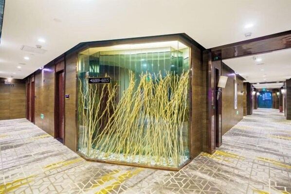 A hotel lobby with a modern design, featuring a glass enclosure with decorative elements and a sign indicating room numbers. - Shenzhen Zhongtian Meijing Hotel (Bao'an International Airport Xixiang Subway Station) (Shenzhen)
