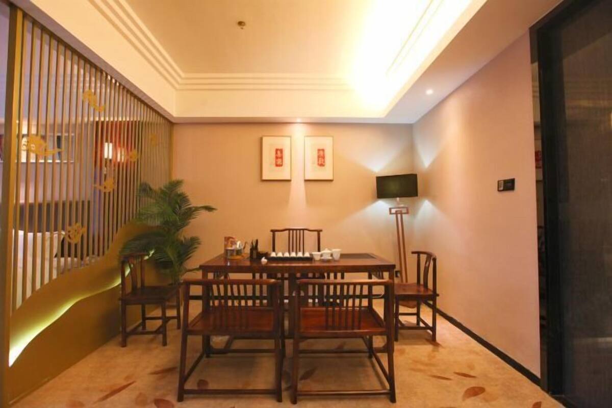 A dining area with a wooden table and chairs, a plant, and a television on a stand.