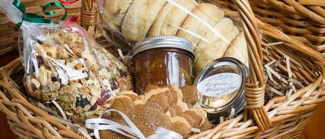 A wicker basket filled with various food items including bread, cookies, and jars of preserves.