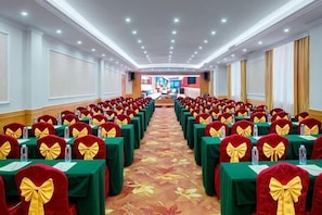 Un salón de conferencias con mesas, sillas en fila y suelo alfombrado.