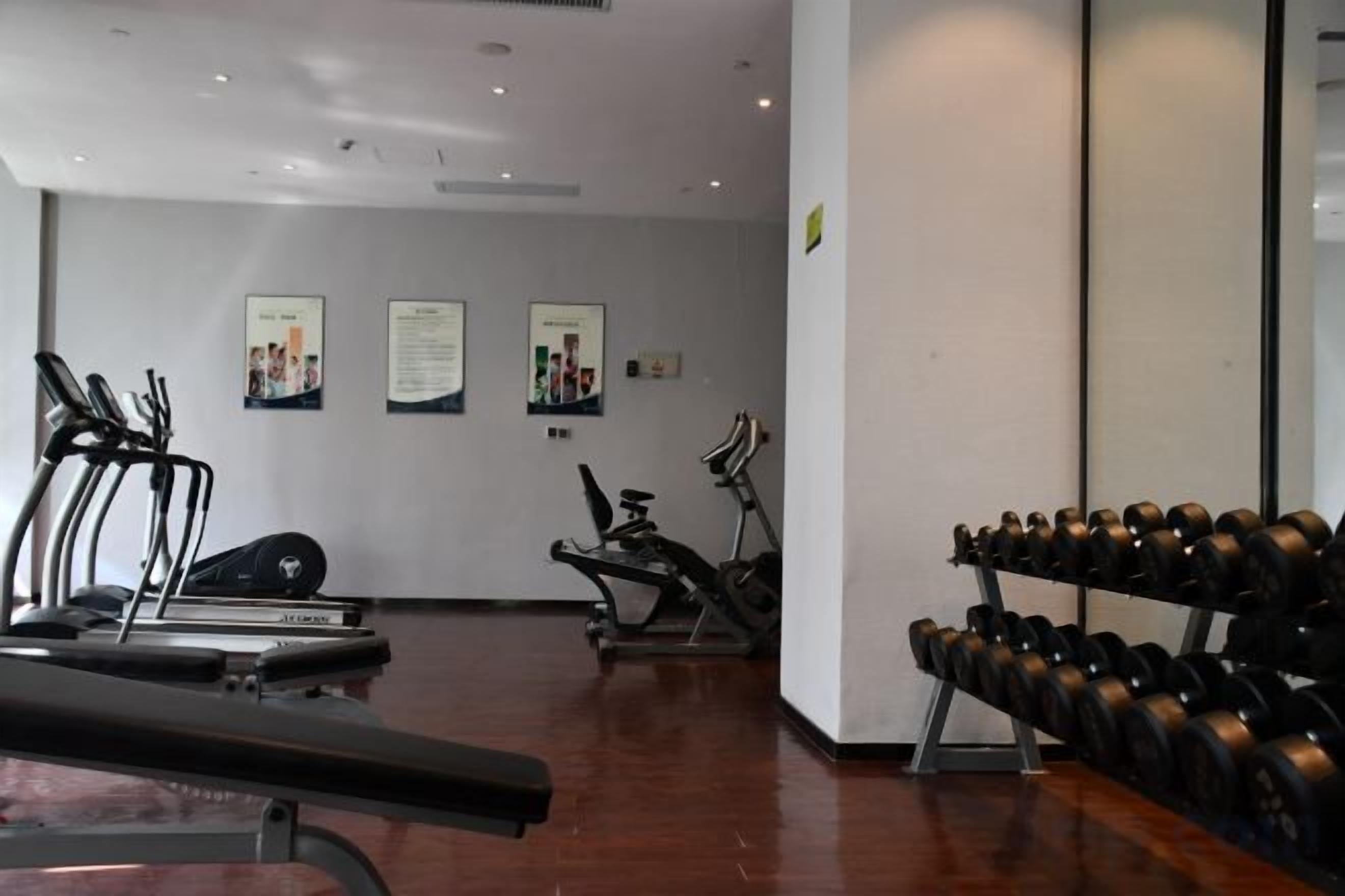 A gym with treadmills, elliptical machines, and a rack of dumbbells.