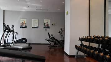 A gym with treadmills, elliptical machines, and a rack of dumbbells.