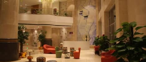 A spacious lobby with multiple seating areas, a high ceiling, and a large map on the wall.