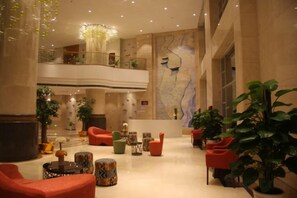 A spacious lobby with multiple seating areas, a high ceiling, and a large map on the wall.