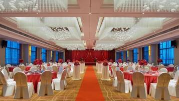 A banquet hall with round tables, a central aisle, and a red carpet.