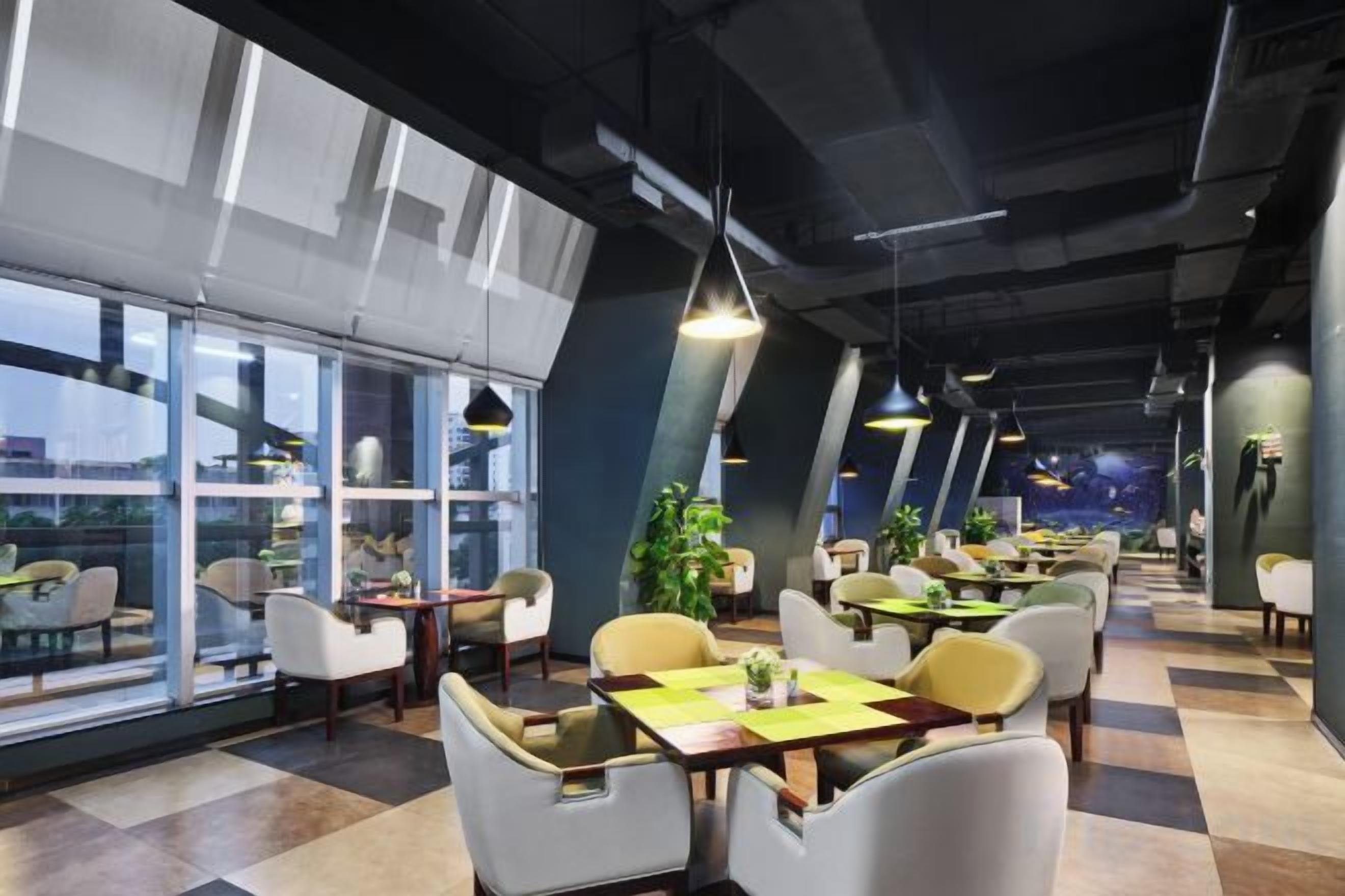 A modern restaurant with high ceilings, large windows, and a checkered floor.