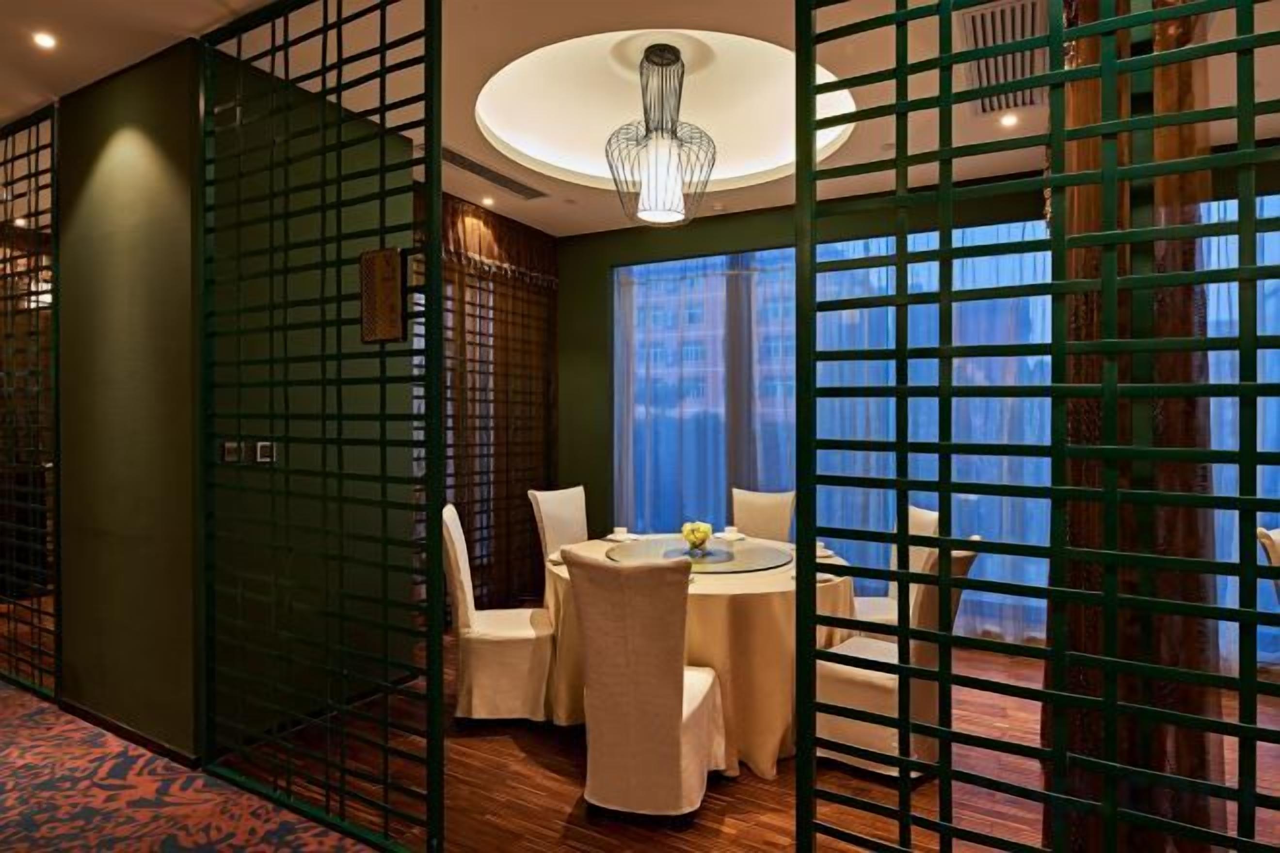 Habitación de hotel con zona de comedor, vistas por la ventana y una lámpara en el techo.