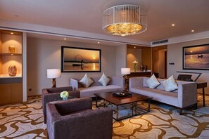 Une chambre d’hôtel moderne, dotée d’un canapé, d’une table basse, d’un lustre et d’œuvres d’art accrochées aux murs.