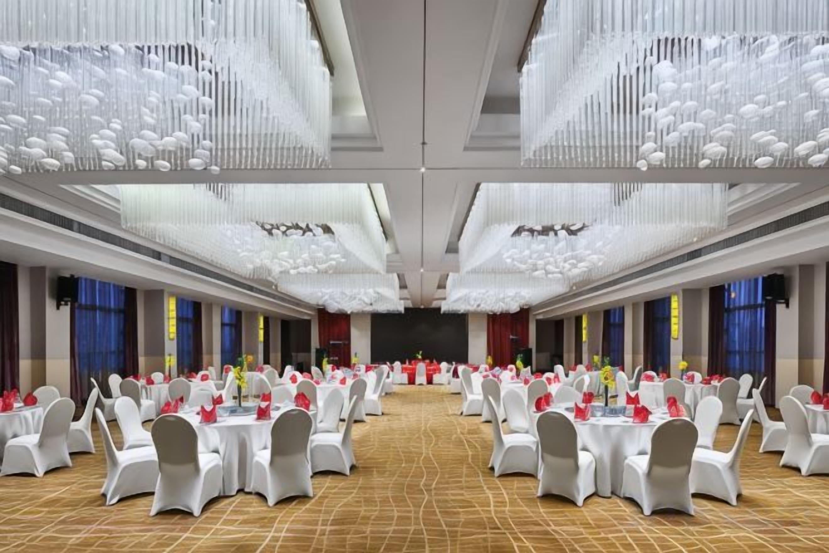 A banquet hall with round tables, chairs, and a stage.