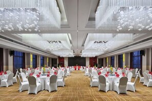 A banquet hall with round tables, chairs, and a stage. - Beihai Hyatt Hotel (high-speed railway station store) (Beihai)