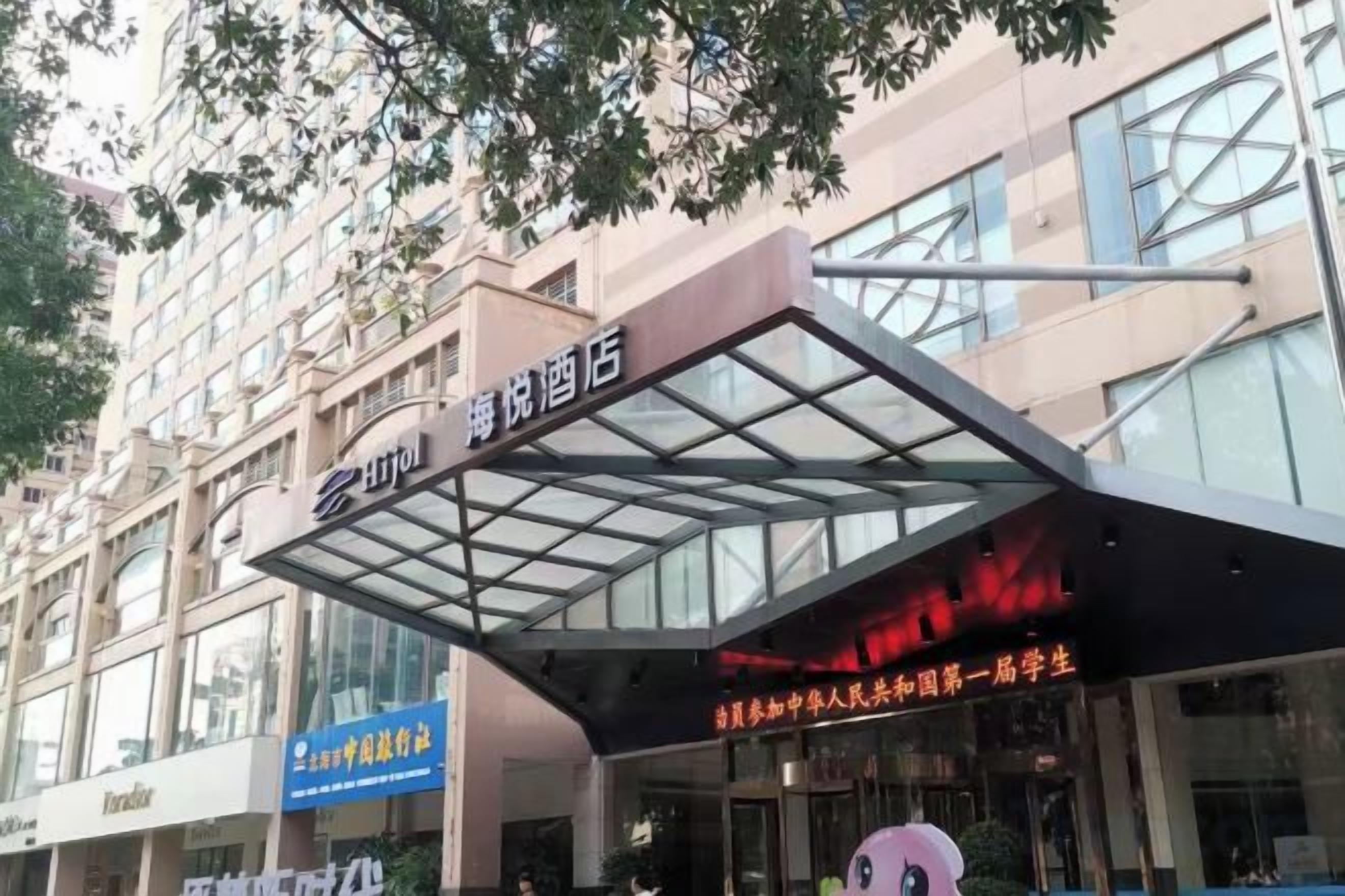 A hotel entrance with a glass canopy and signage in a foreign language.