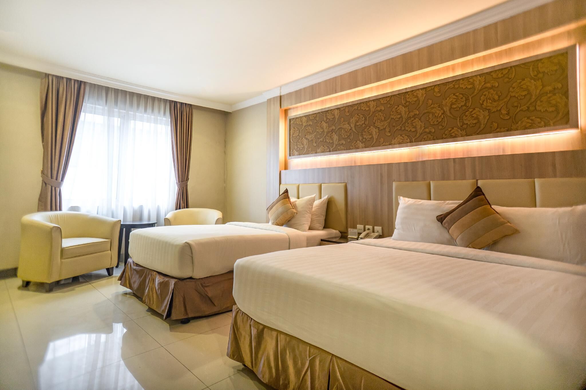 A hotel room with two beds, a sofa, a small table, and a decorative wall panel.
