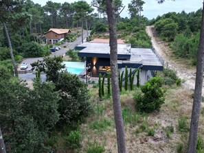 Enjoy a relaxing stay in this two-story house with a spacious backyard, featuring a swimming pool and covered outdoor seating area surrounded by lush greenery and trees.
