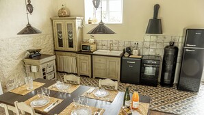 A kitchen with a dining table set for four, a microwave, a stove, and a refrigerator. - A house of charm and history (Picauville)