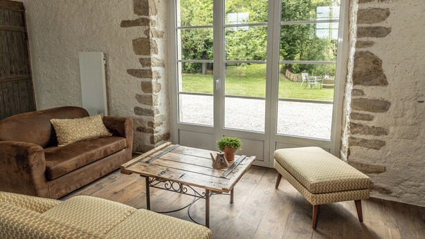 A room with a brown leather sofa, a wooden coffee table with a potted plant, and a bench. - A house of charm and history (Picauville)