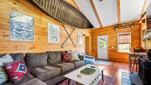 A cozy cabin interior with a wooden interior, a sofa, a coffee table, and a fireplace. - Charming Farmhouse, Sauna - 4 bedrooms, WiFi, AC in Upper Jay (Upper Jay)