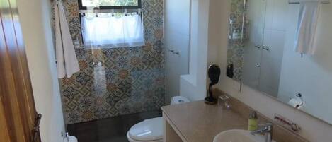 Un baño con inodoro, lavabo y zona de ducha.