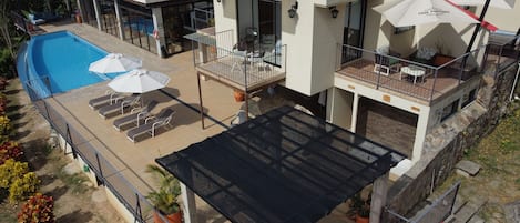 A modern hotel with a swimming pool, outdoor seating, and a covered patio area.