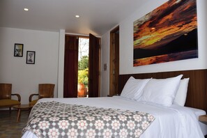 Une chambre d’hôtel avec un lit, deux chaises, un tableau et une vue sur l’extérieur.
