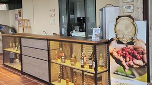 A cafe with a counter displaying various beverages, a sign indicating 'SALON VALERIANOS', and a poster advertising coffee. - Hotel Casa Portones  (San Bernardo)