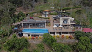 Un immeuble moderne à plusieurs étages, doté d’une piscine, d’un espace extérieur aménagé et offrant une vue sur le paysage environnant.