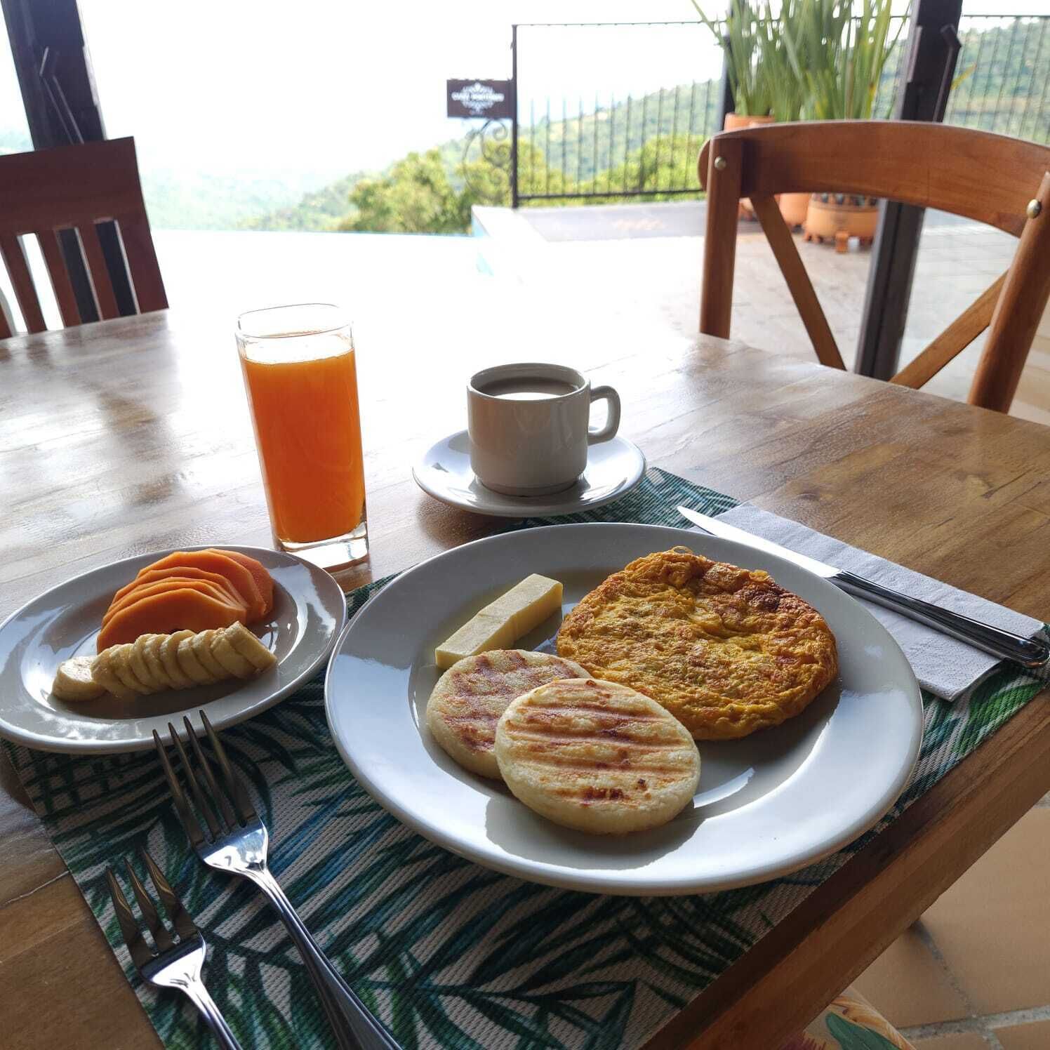 Ein Frühstückstisch mit einem Teller Essen, einem Glas Orangensaft und einer Tasse Kaffee.