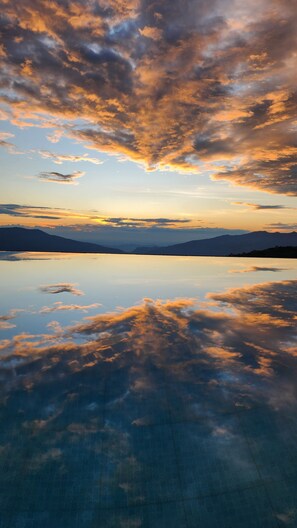 Eine friedliche Landschaft mit einem stillen See, der den Himmel und die entfernten Berge spiegelt.