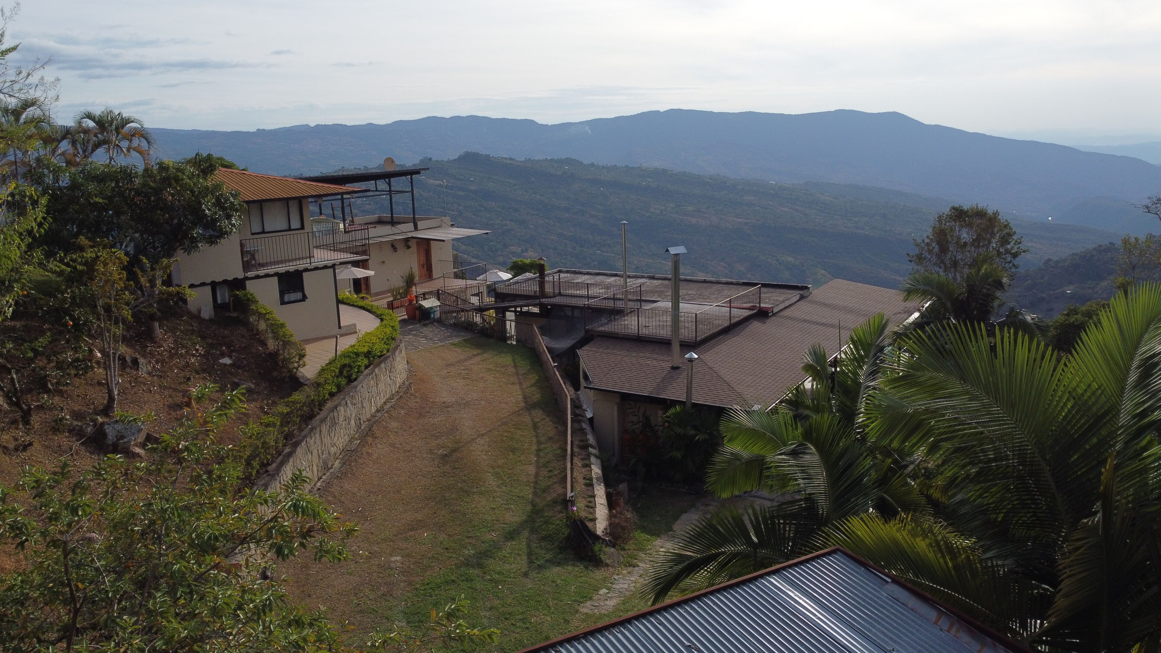 A residential area with a house featuring a balcony and a view of distant mountains.