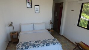 Une chambre à coucher avec un lit, deux tables de chevet, une fenêtre et une porte.
