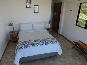Une chambre à coucher avec un lit, deux tables de chevet, une fenêtre et une porte.