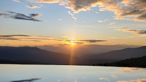 A clear sky with clouds and the sun setting over a calm body of water. - Hotel Casa Portones  (San Bernardo)