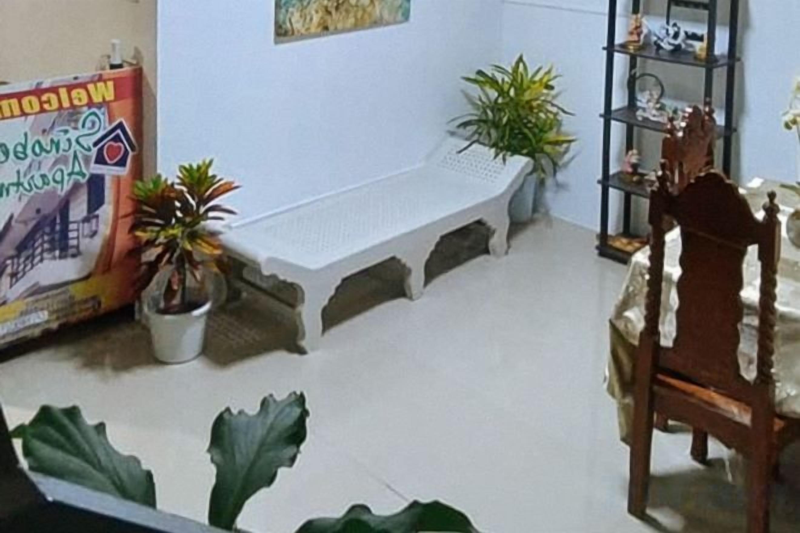 A room with a wooden chair, a bench, and potted plants.