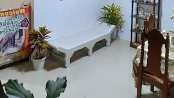 A room with a wooden chair, a bench, and potted plants.