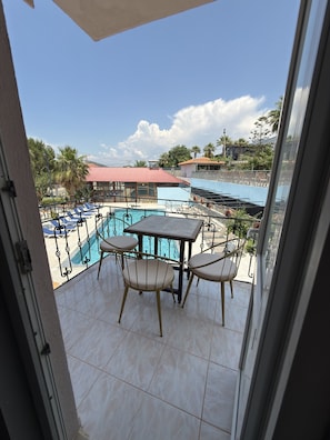 A balcony with a pool, chairs, and a table.