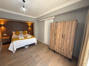 A bedroom with a bed, bedside tables, a wardrobe, and a hanging light fixture.