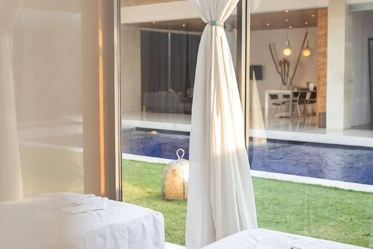 A bedroom with a view of a swimming pool and a dining area.