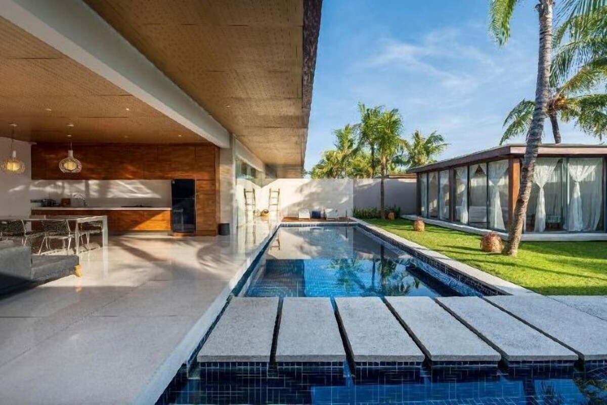 A modern pool area with a clear view of the pool, a bar area, and a covered outdoor space.